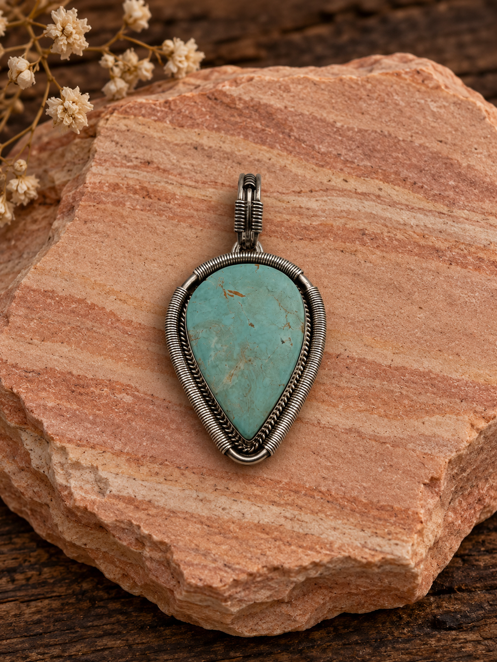 Pale turquoise teardrop sterling silver pendant with coiled silver border on rose sandstone