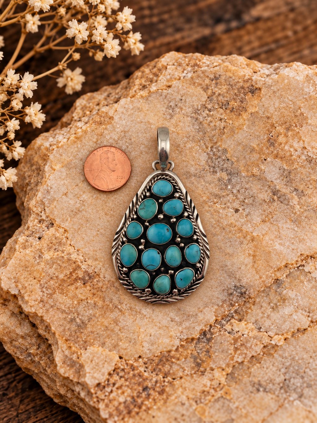 Turquoise teardrop cluster pendant signed B Johnson, .925 sterling silver, detail with penny on styled stone background