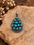 Turquoise teardrop cluster pendant signed B Johnson in .925 sterling silver on styled stone background