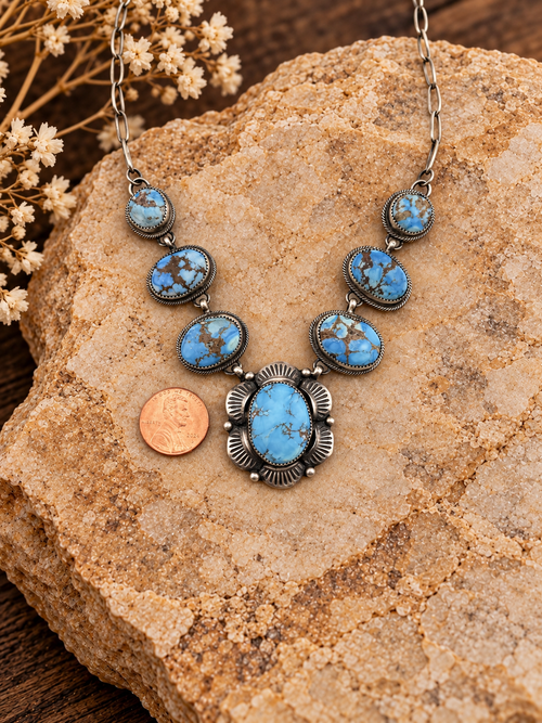 Bob Becenti seven-stone turquoise sterling silver necklace detail with penny and styled stone background