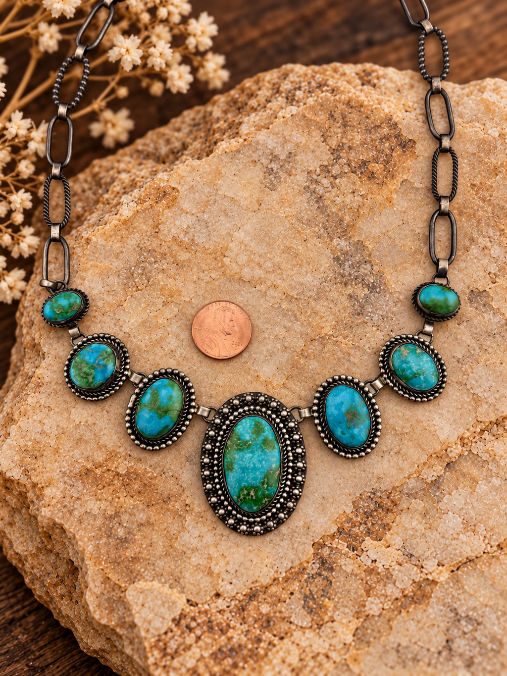 Seven-stone turquoise sterling silver necklace detail with styled stone background and penny