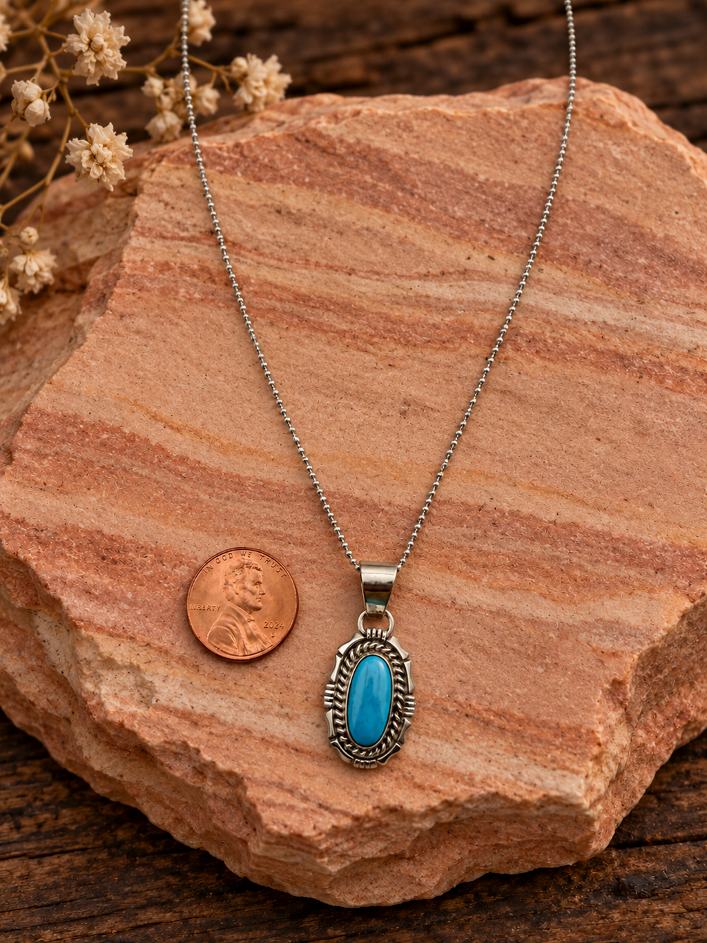 Oval turquoise pendant with sterling silver chain and penny on rose sandstone