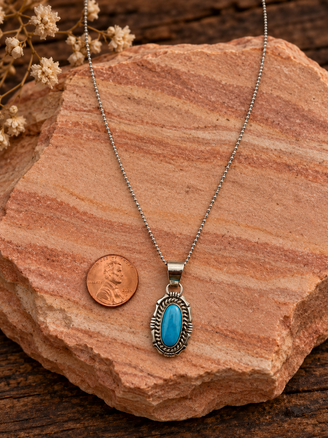 Oval turquoise pendant with sterling silver chain and penny on rose sandstone