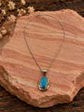 Oval turquoise pendant in ornate sterling silver setting with included sterling silver chain on rose sandstone